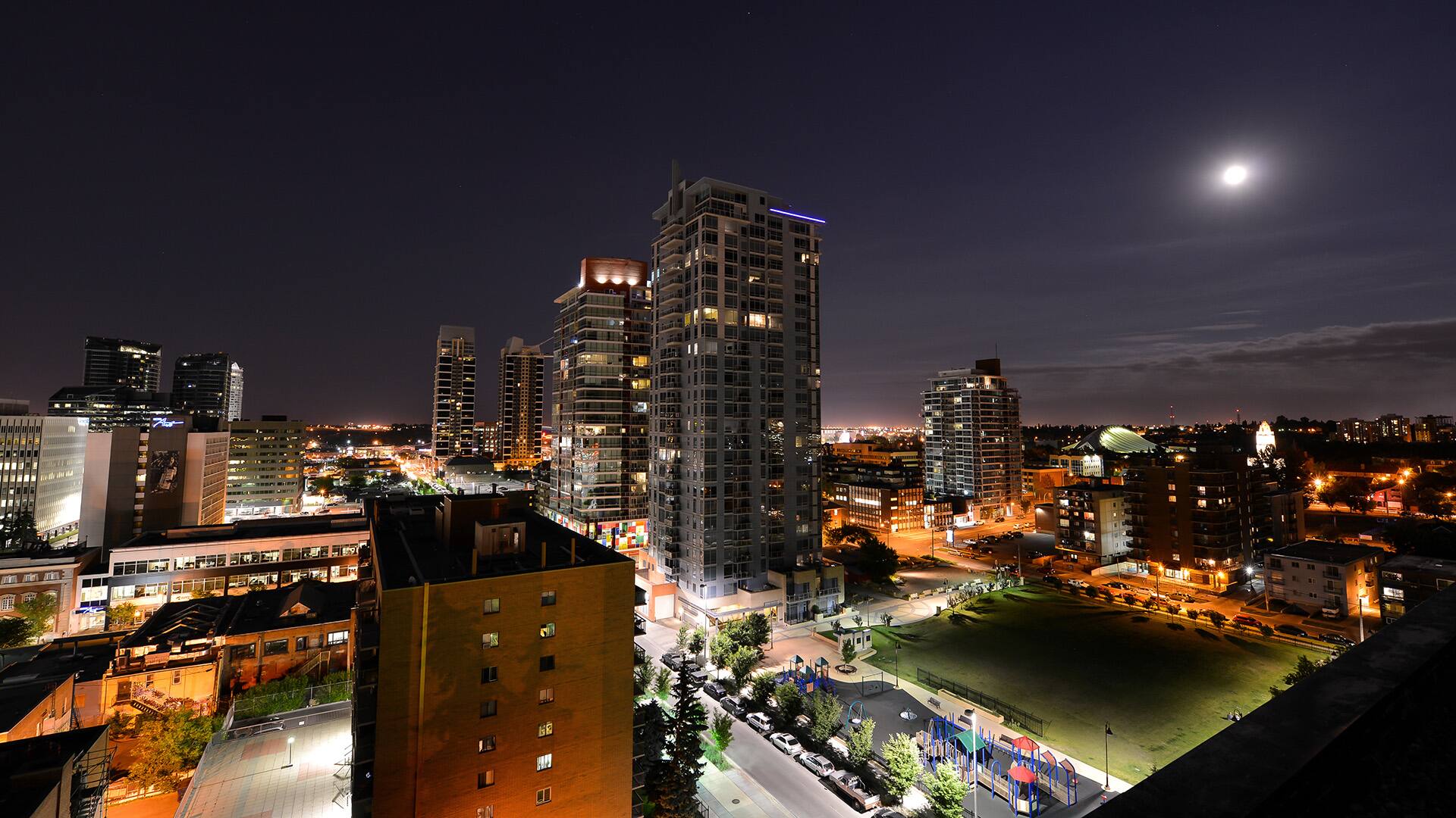 A warm Summer evening with the Moon rising over the Beltline, in Calgary Alberta