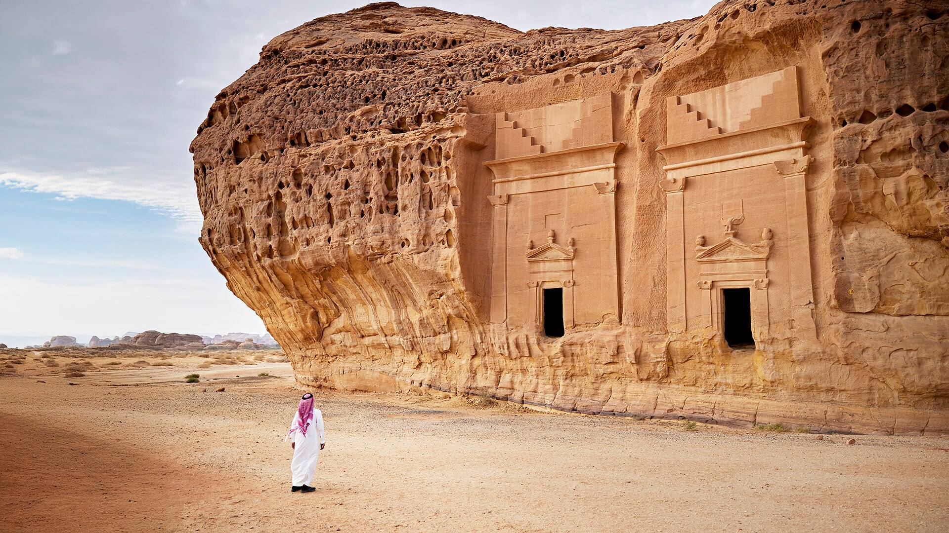 Saudi man admiring ancient rock-cut architecture at Hegra