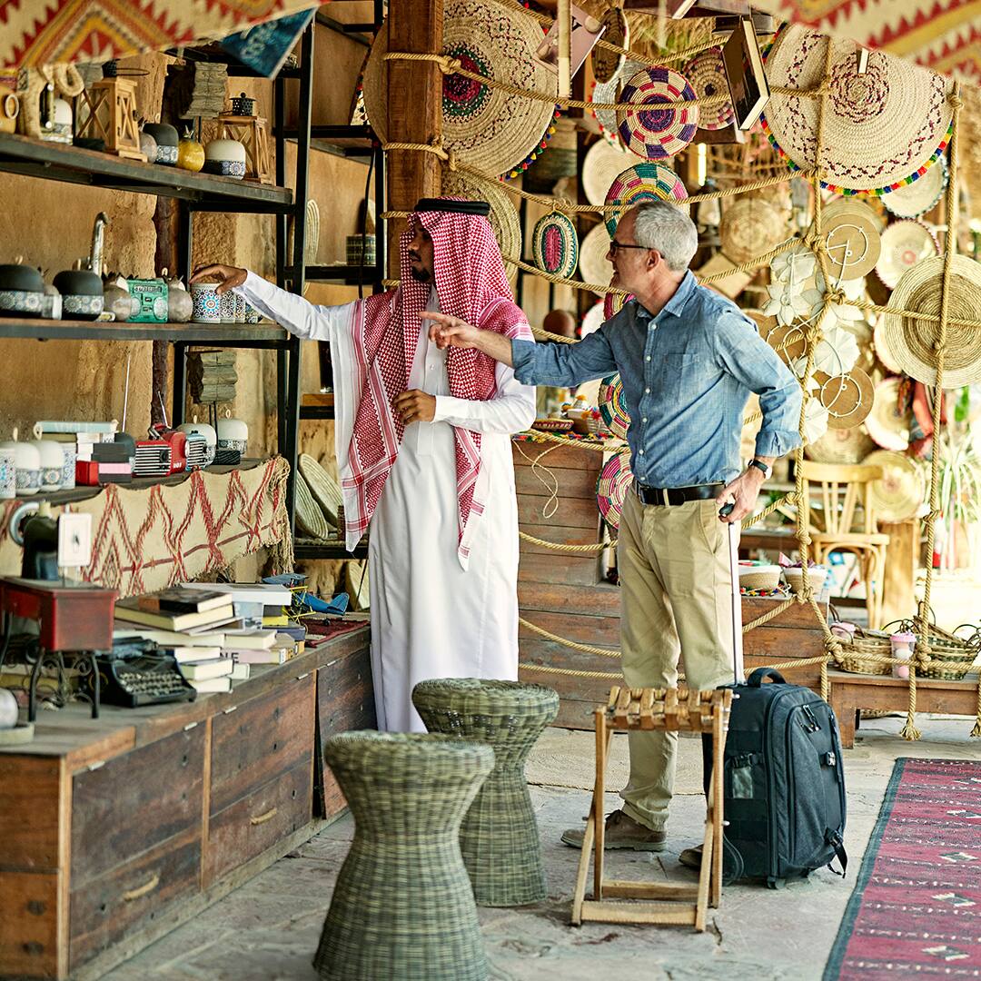 Saudi merchant and tourist looking at craft products