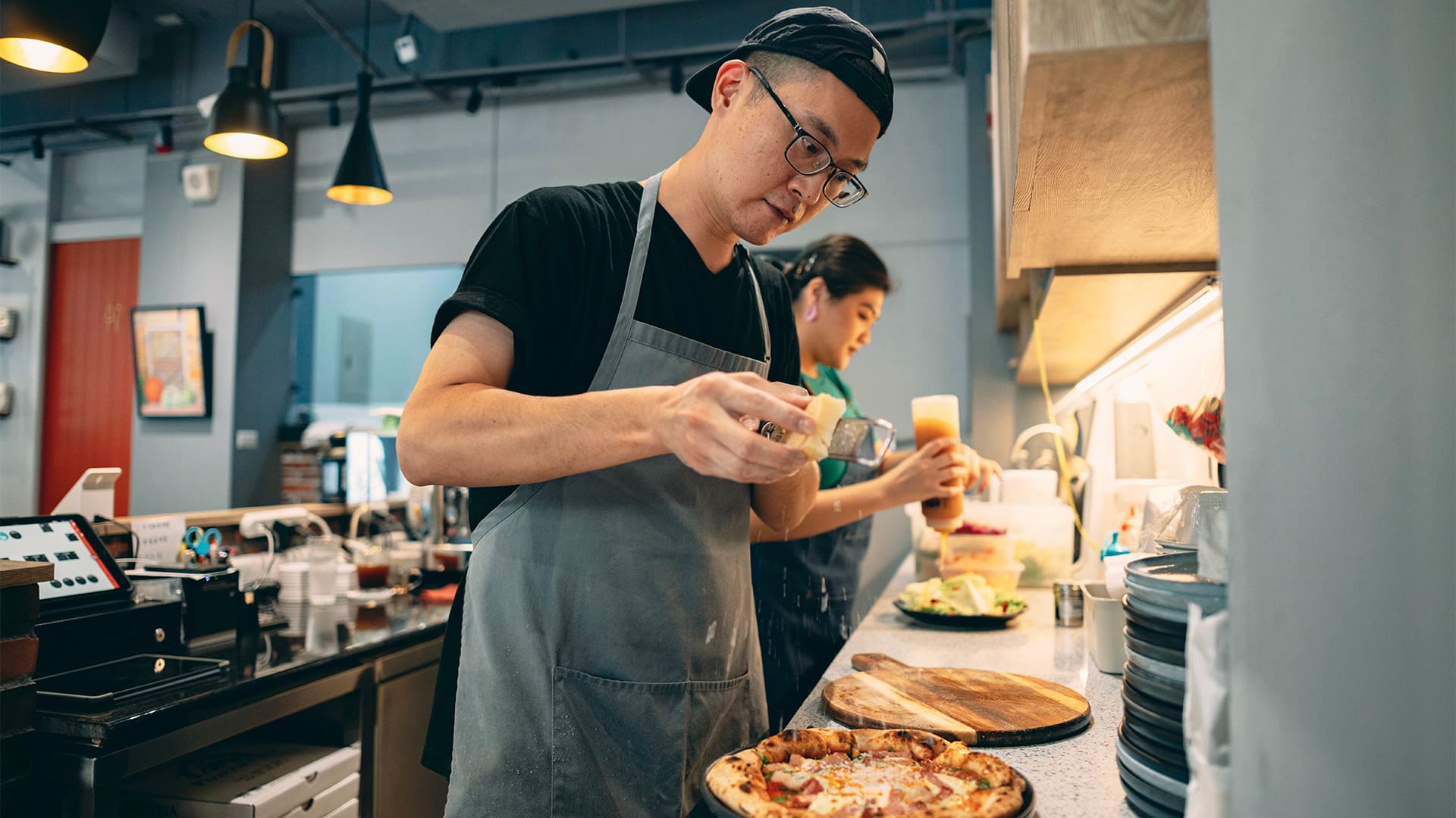 Two Asian restaurant staff members are working in the kitchen, collaborating to create delicious meals