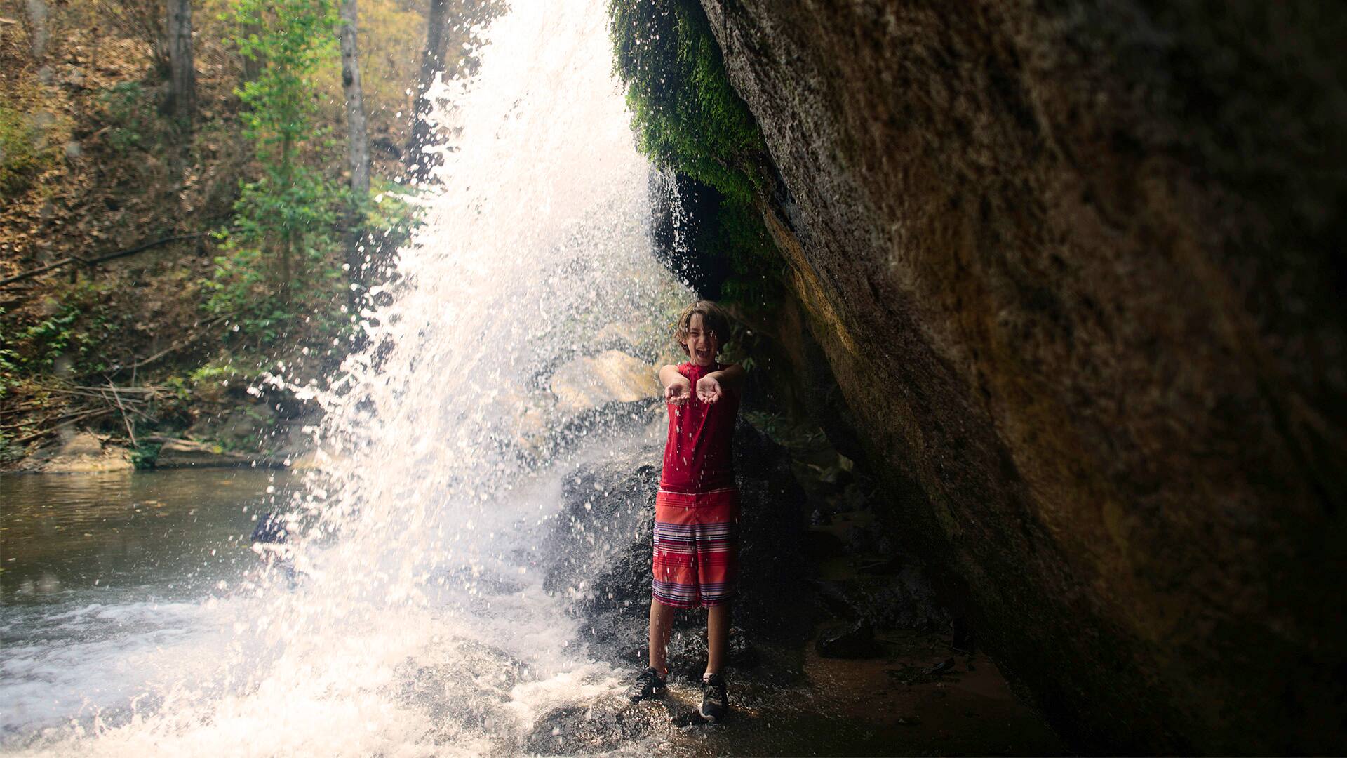 High angle view of girl with arms outstretched standing at Bua Thong Waterfalls
