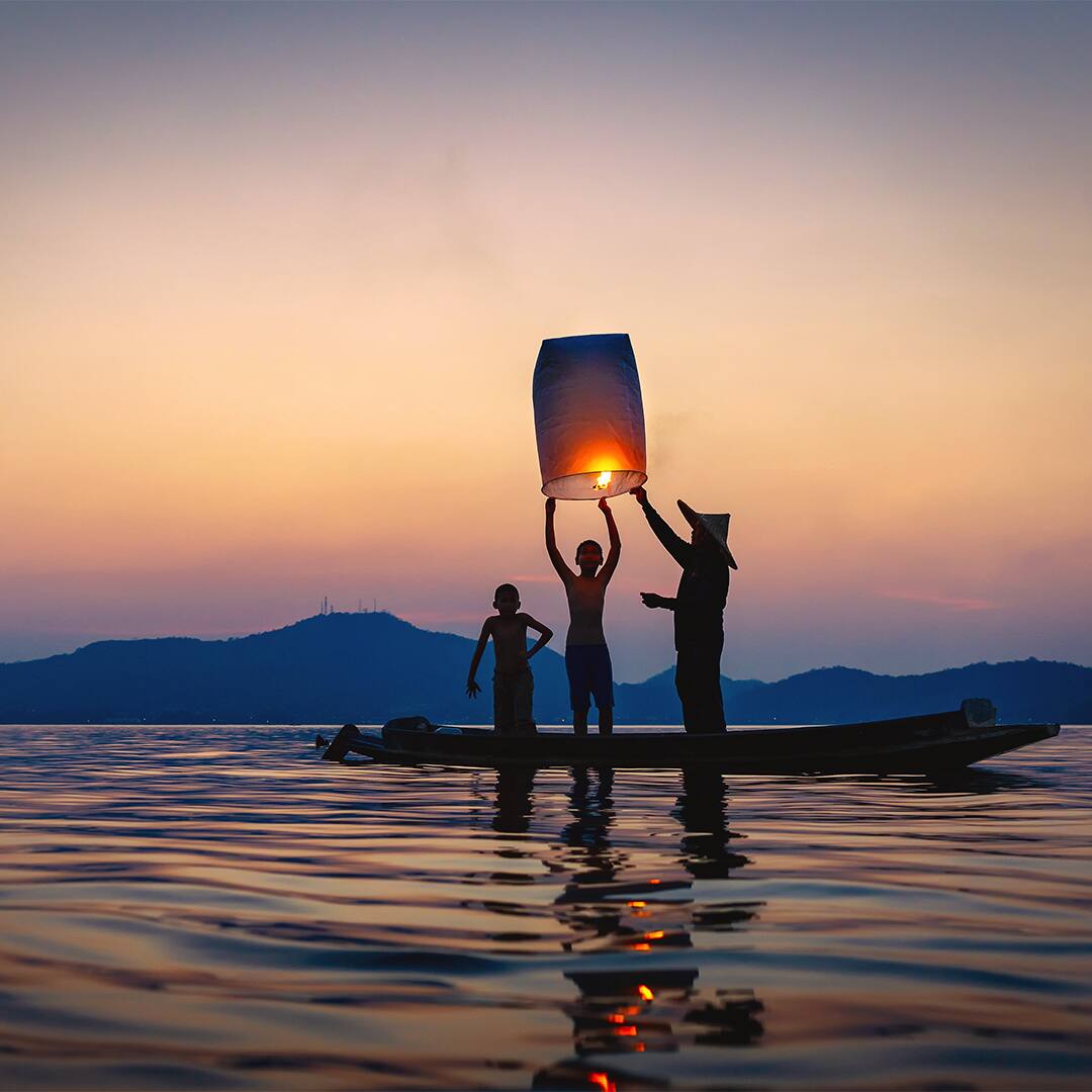 Fisherman on wooden boat with floating lamp