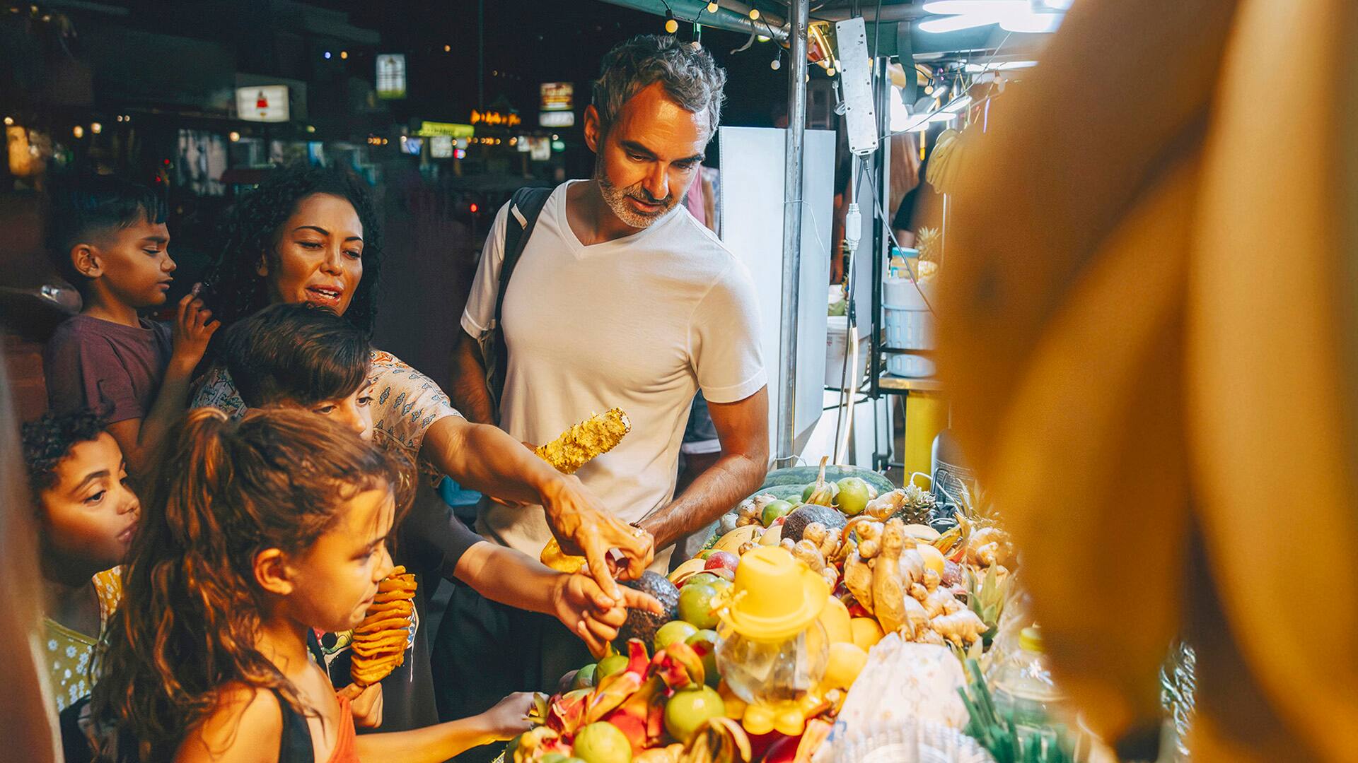 Tourist family choosing fruits from stall at food market