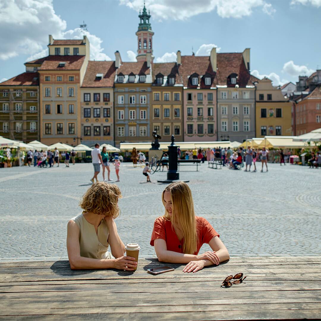 Two happy female friends socializing on a town square in summer