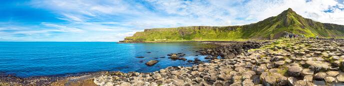 green cliffs on coastline of ireland with sea and blue sky behind