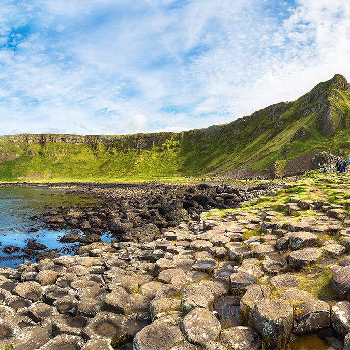 green cliffs on coastline of ireland with sea and blue sky behind