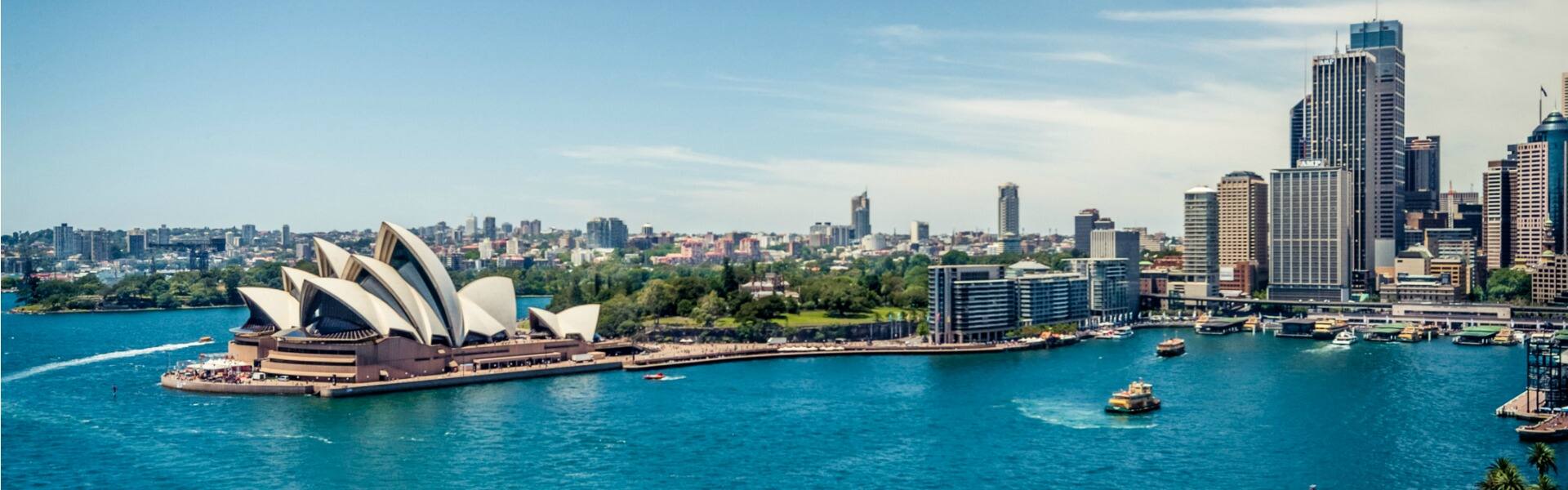 view of the opera house in sydney harbour with boats in the foreground on a sunny day