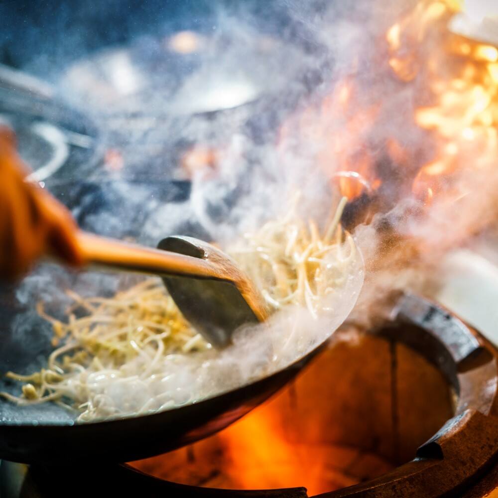 noodles being stir fried in a wok hong kong