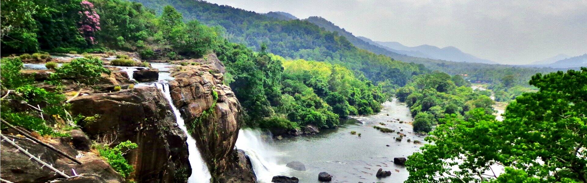 the spectacular athirapally waterfall in kerala with a view of the surrounding jungle and mountains