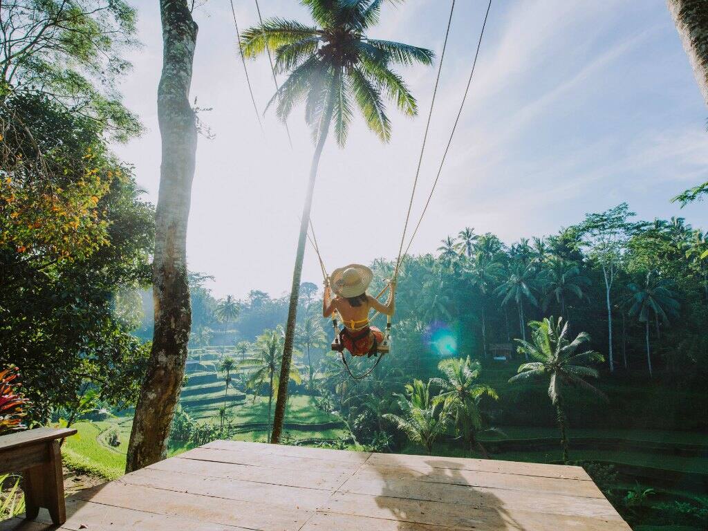 a girl swinging over the bali rice fields in ubud indonesia