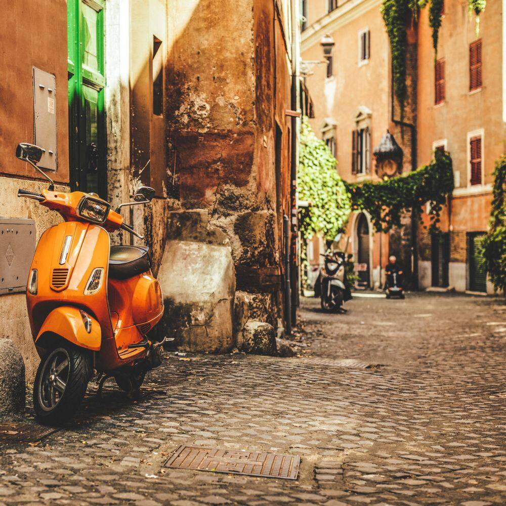 a street with an orange motorbike in trastevere rome
