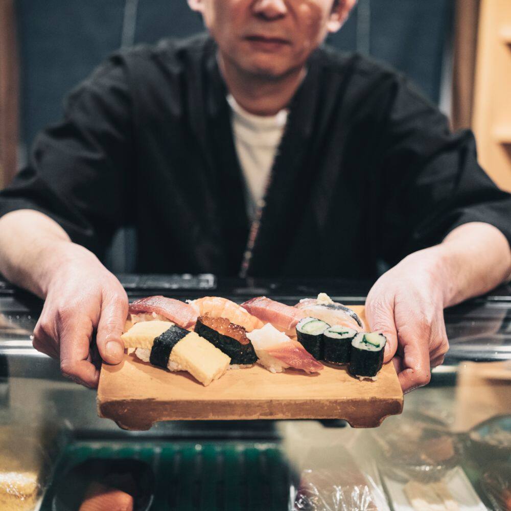man holding a board of sushi tokyo japan