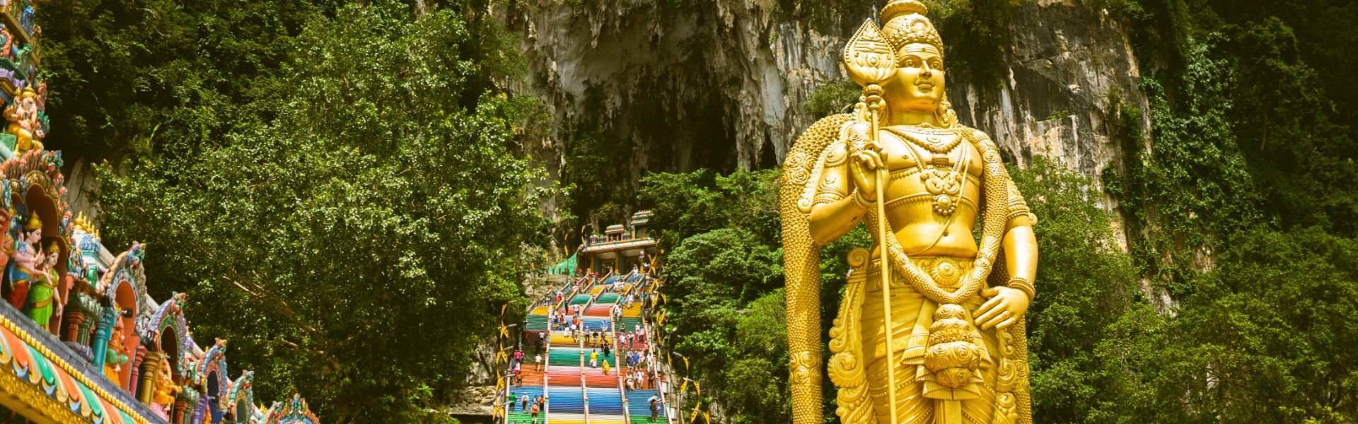 a giant statue of a golden buddha outside the batu caves in malaysia 