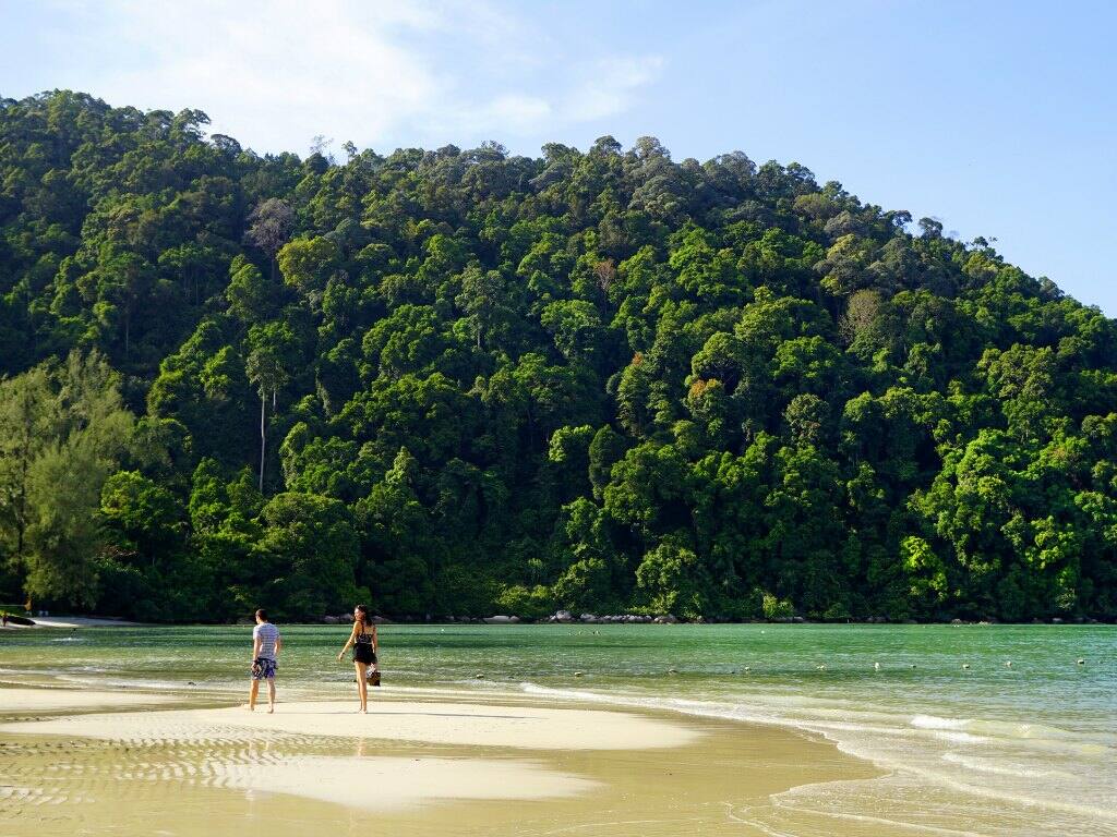 a couple walking along the shoreline on monkey beach in penang malaysia
