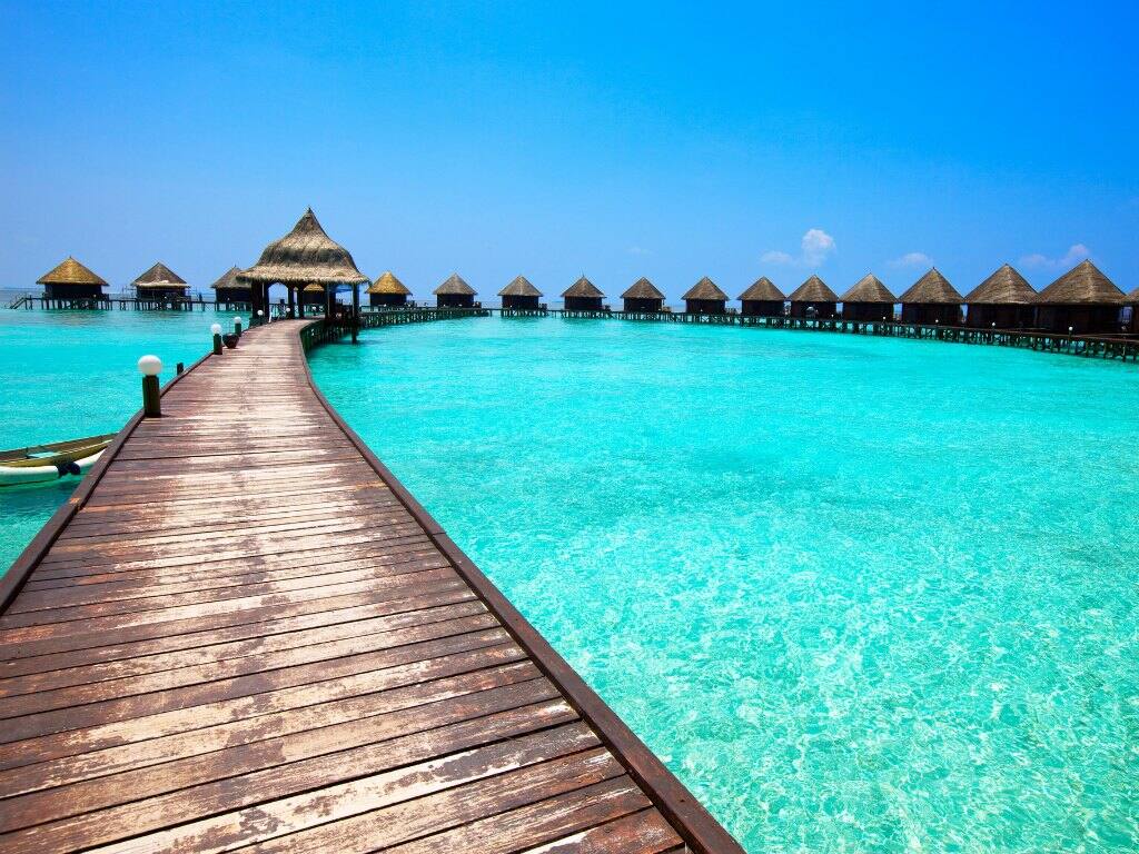 a wooden walkway leading to water villas in the maldives