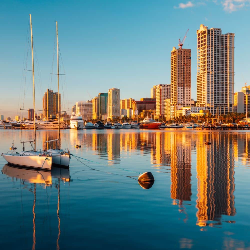 manila skyline from the harbour side with boats in the foreground philippines