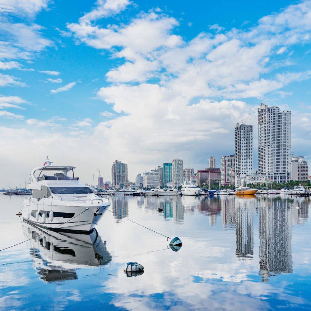 manila harbour on a sunny day with a yacht in the foreground manila