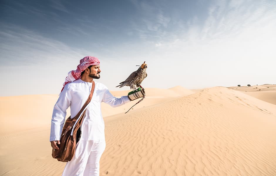 man holding bird in desert