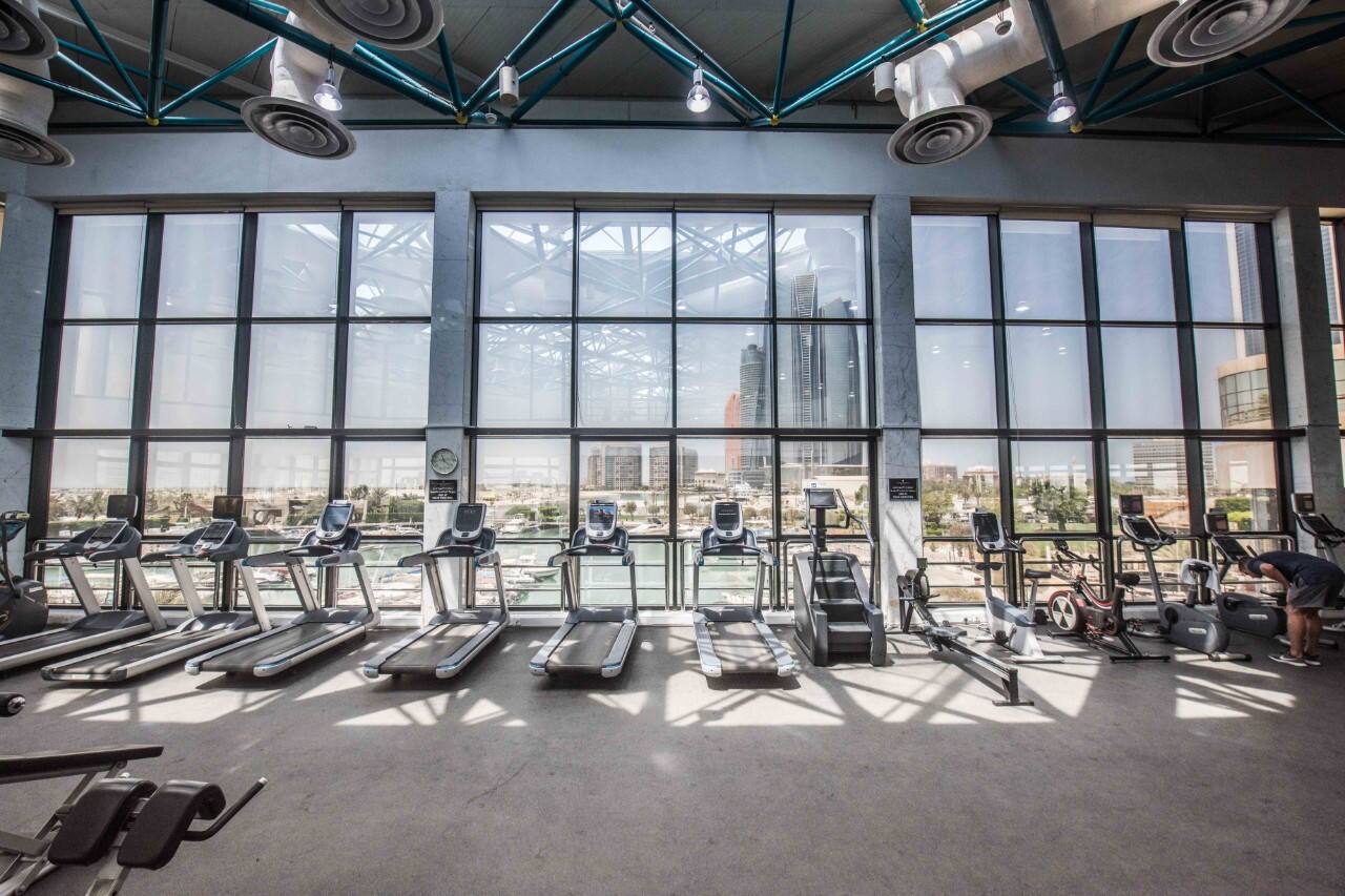 treadmills in gym with view of downtown abu dhabi through large windows