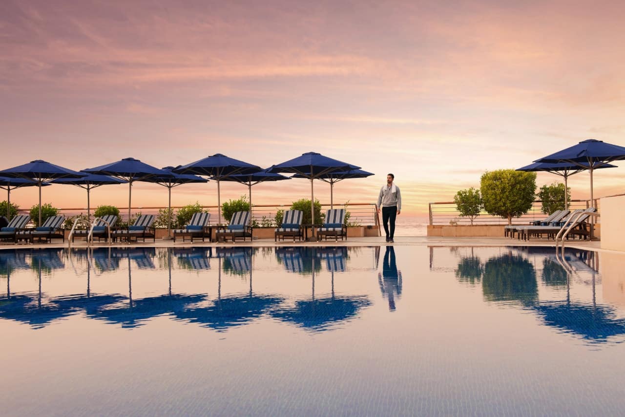 swimming pool surrounded by sun loungers and parasols at dusk