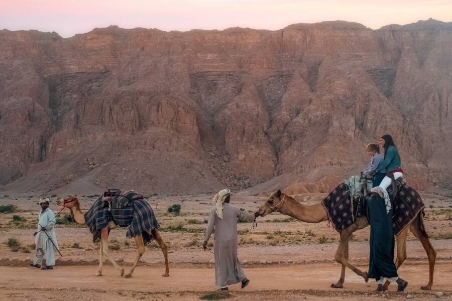 people walking through jebel hafeet with camels