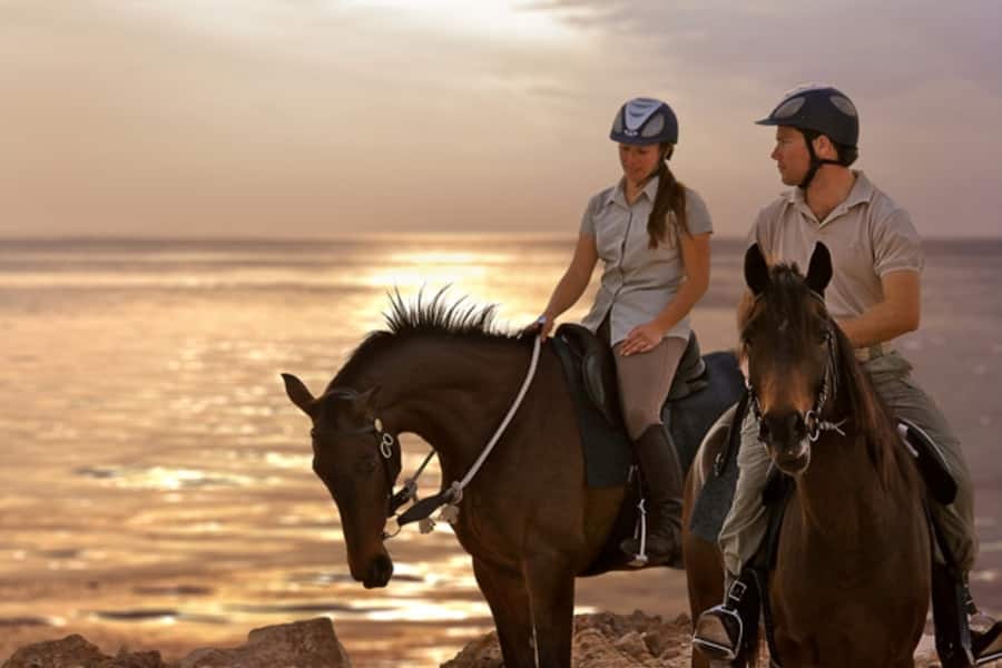 two people horseriding at sunset