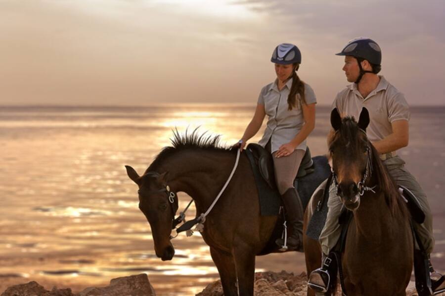 two people horseriding at sunset