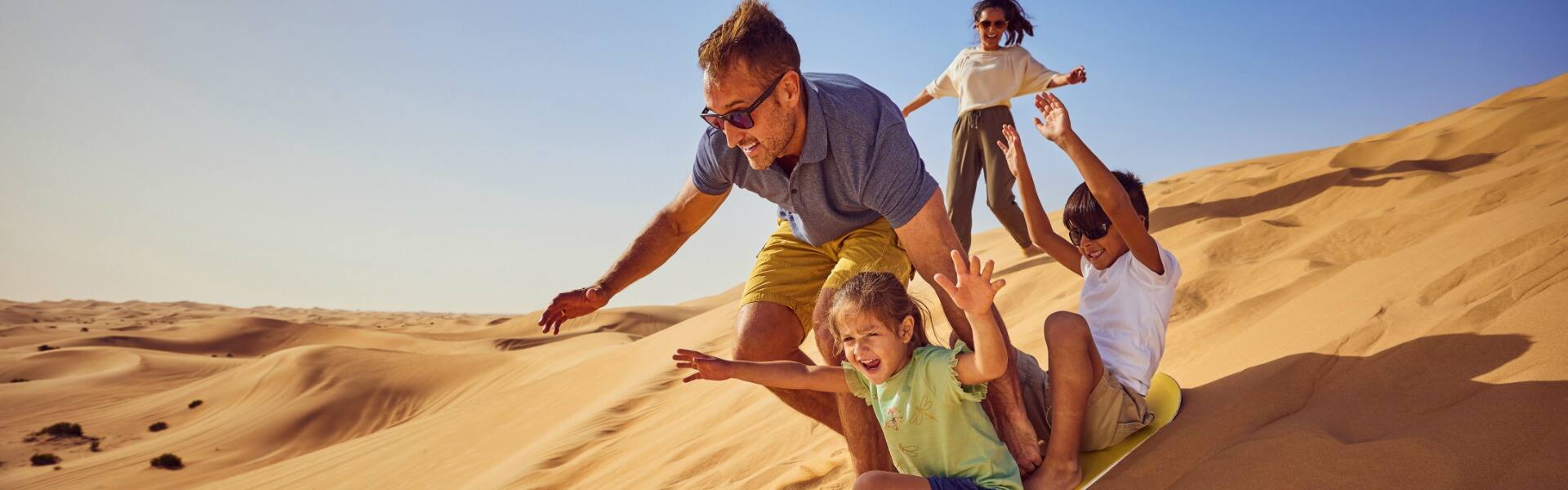 a family enjoying desert surfing down sand dunes in the united arab emirates