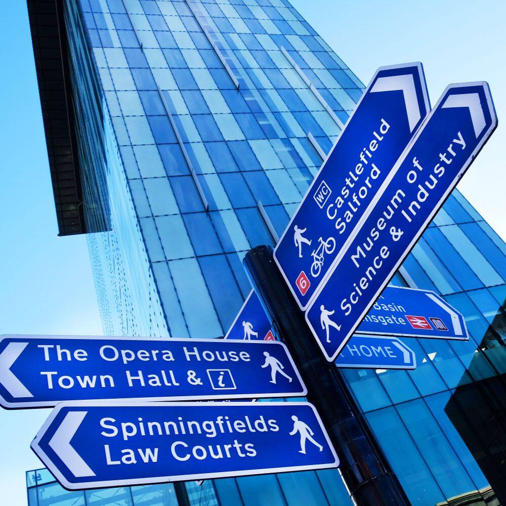 various blue street signs of manchester including sign for museum of science 